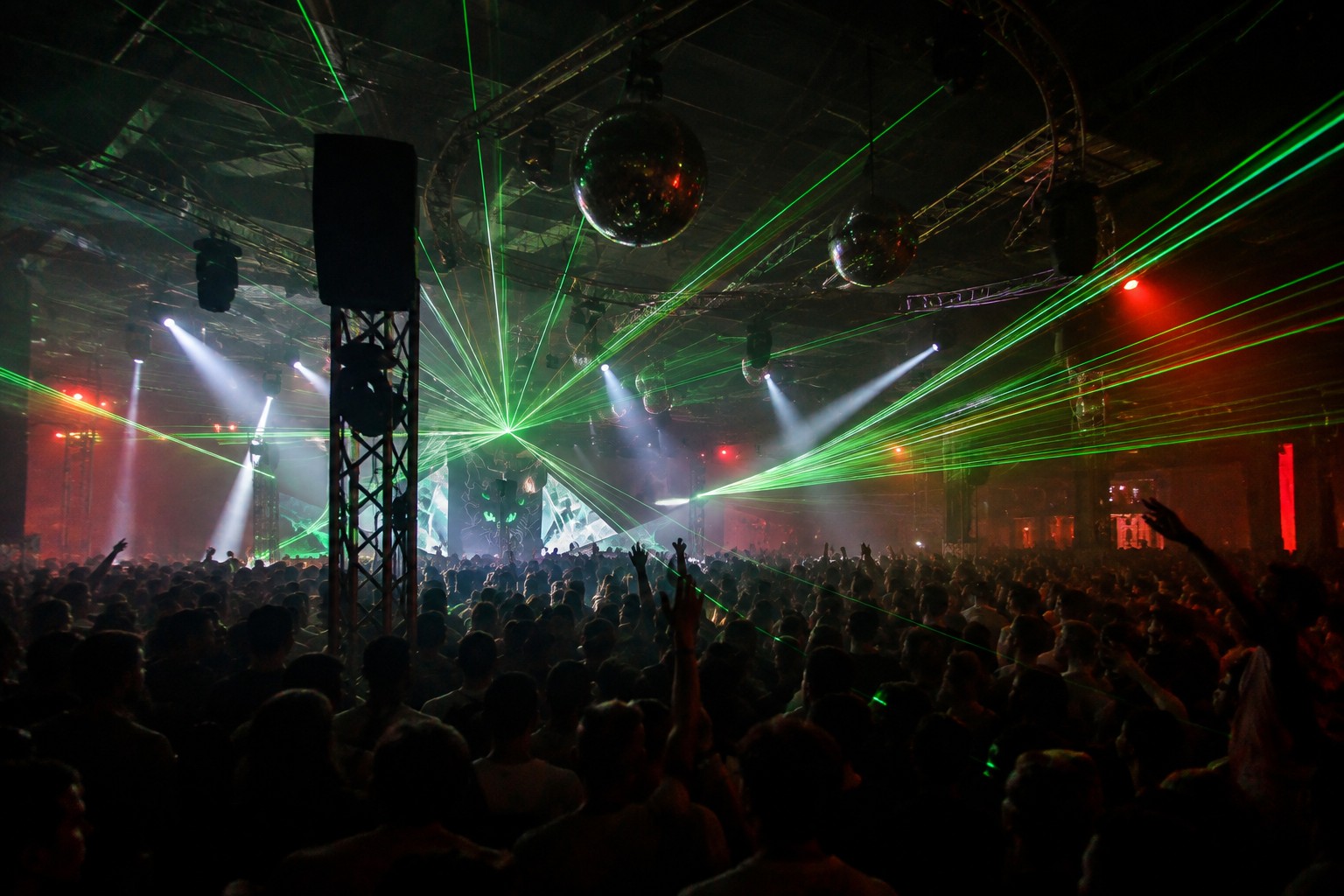 Large nightclub crowd beneath green lasers and disco balls